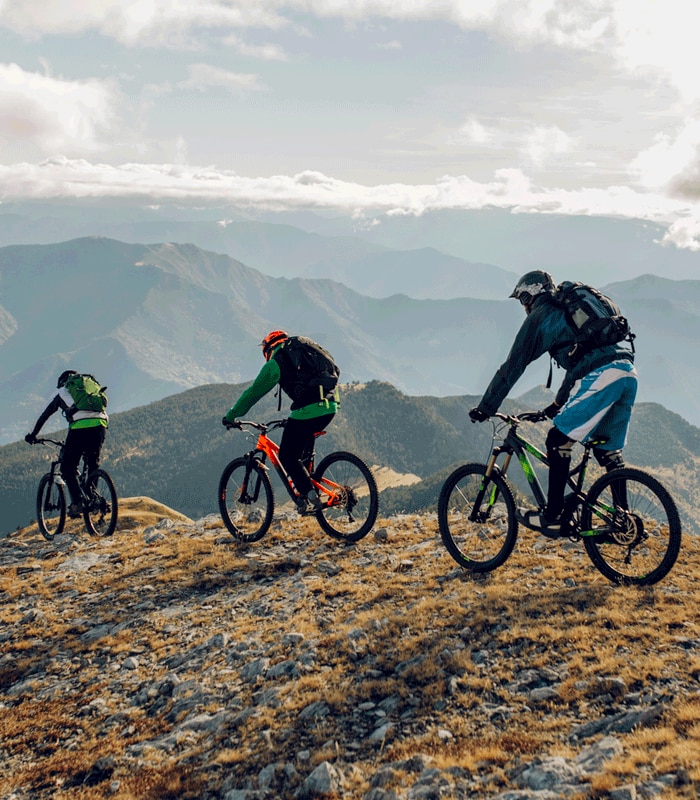 Three adventurers traversing mountain top on their bikes